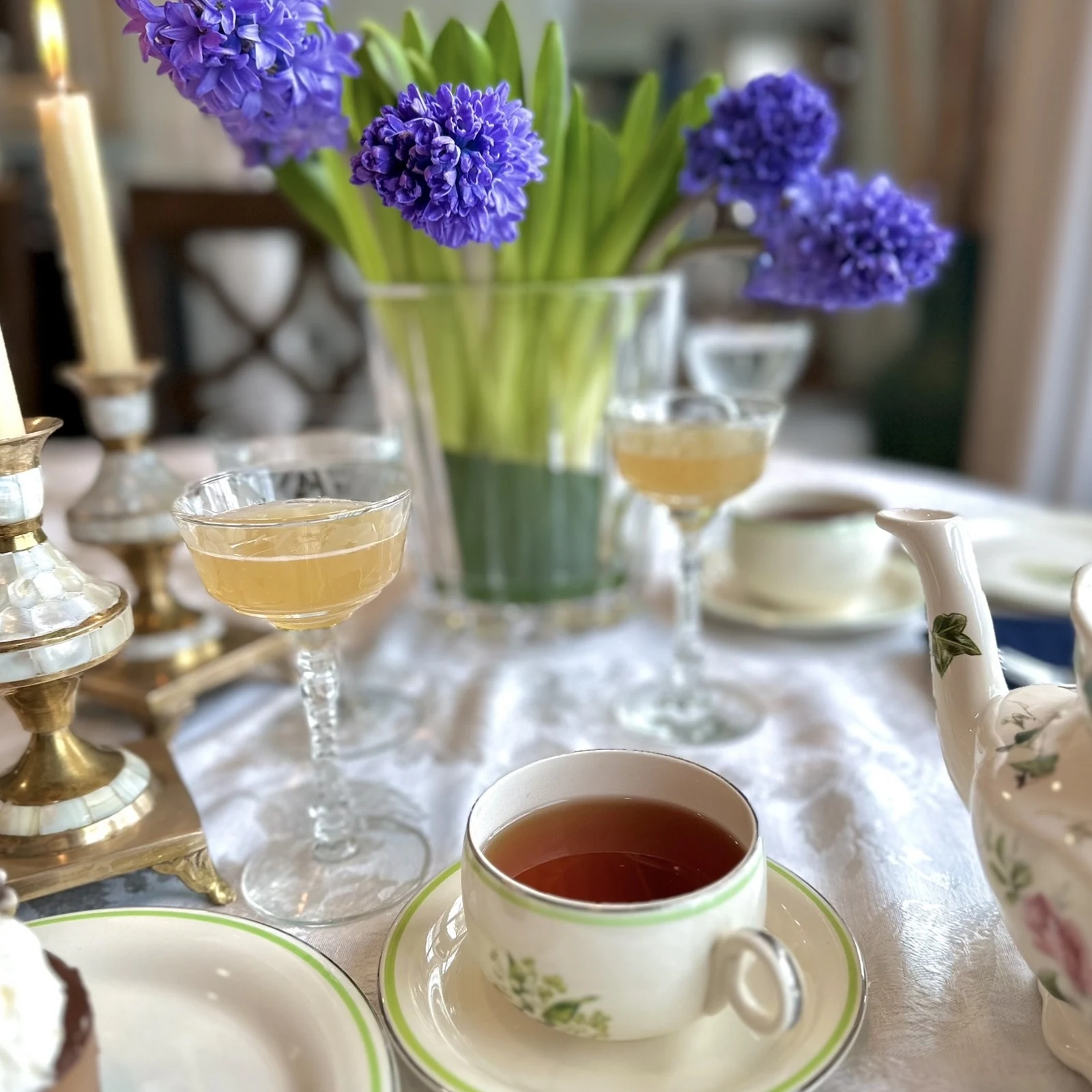 Purple hyacinths, candlelight and tea in green-edged china