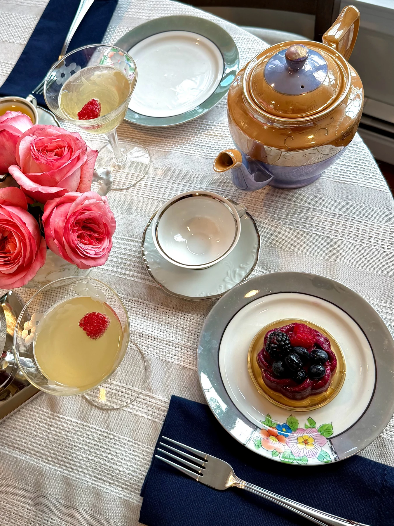 A Rugby Reserve place setting with navy linen, a berry tart and a distinctive teapot