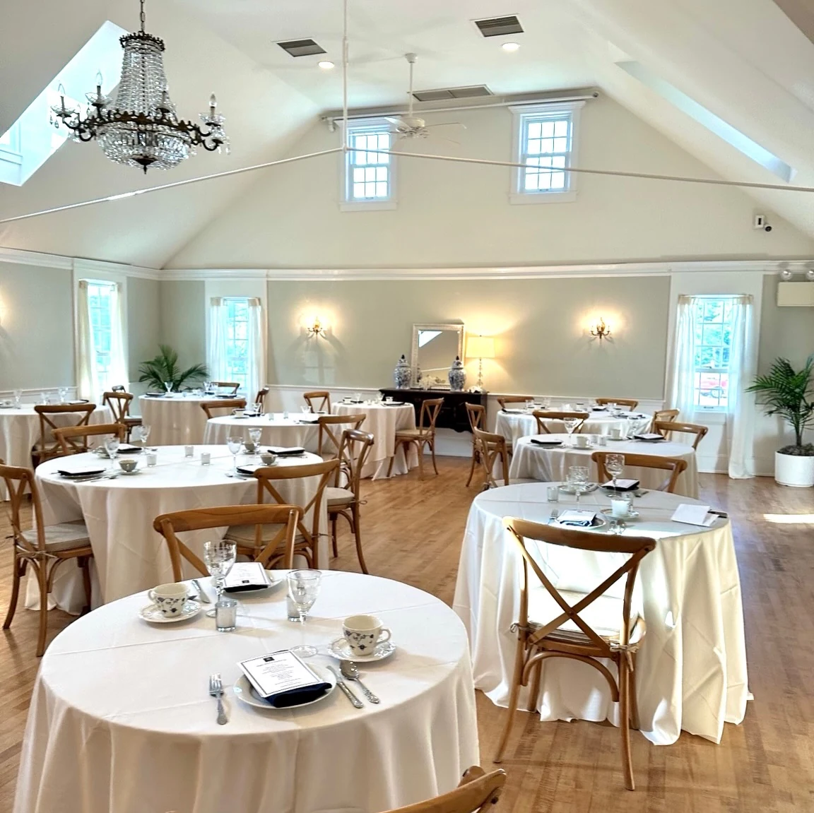A chandelier above linen-covered tables prepared for Rugby Reserve afternoon tea